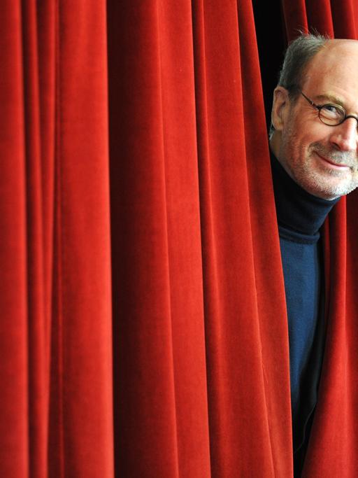 Der Geschäftsführende Direktor des Deutschen Bühnenvereins, Rolf Bolwin, schaut im Deutschen Schauspielhaus in Hamburg zwischen einem Theatervorhang hervor.