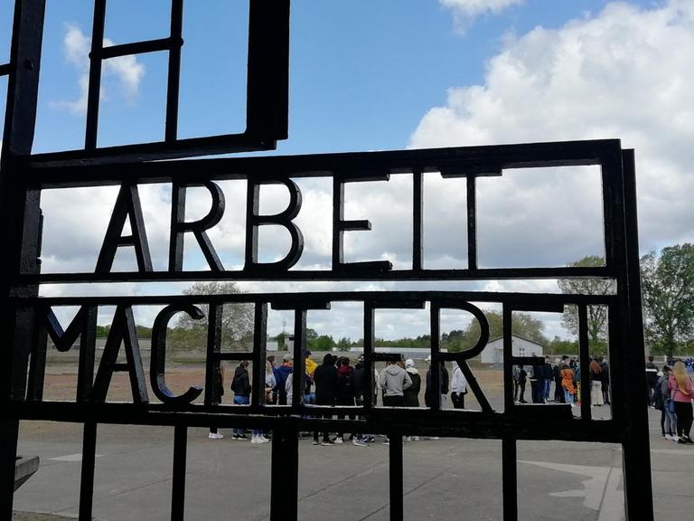 Das Bild zeigt ein Tor im ehemaligen KZ Sachsenhausen, das den Spruch "Arbeit macht frei" trägt.