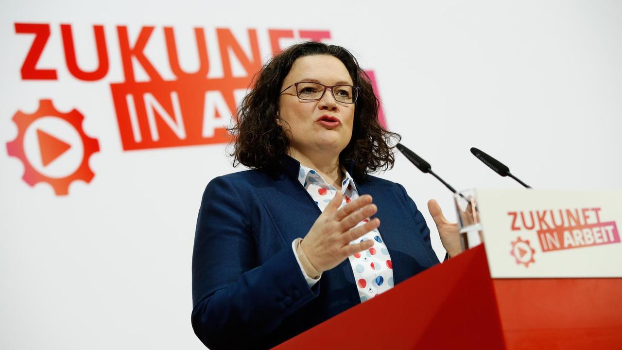 Andrea Nahles an einem Rednerpult vor einem SPD-Logo mit der Aufschrift "Zukunft in Arbeit". 