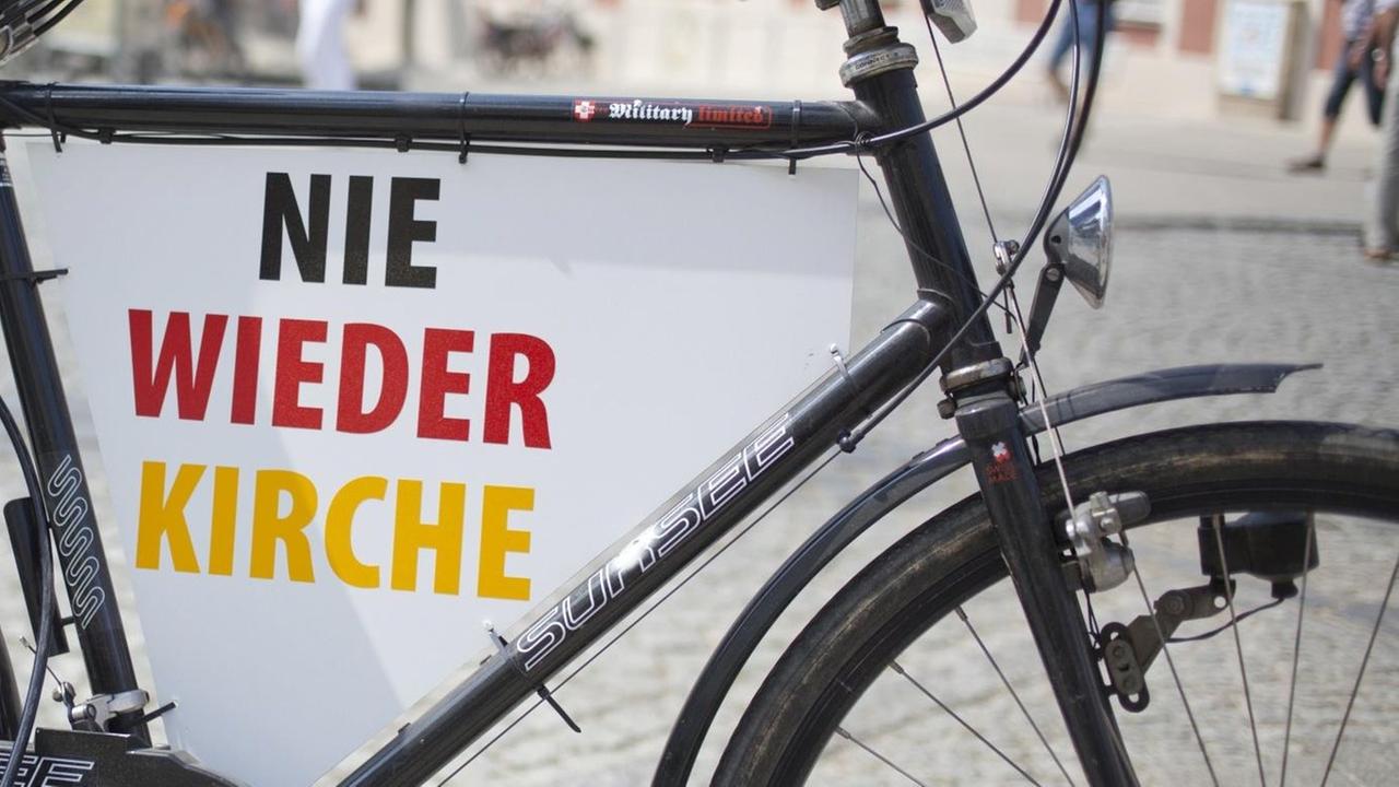 Ein Fahrrad mit der Aufschrift "Nie wieder Kirche" in Schwarz-Rot-Gold.