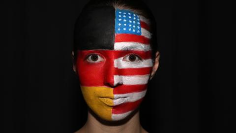 Frau mit geschminktem Gesicht, das die Farben der deutschen und amerikanischen Flagge zeigt.