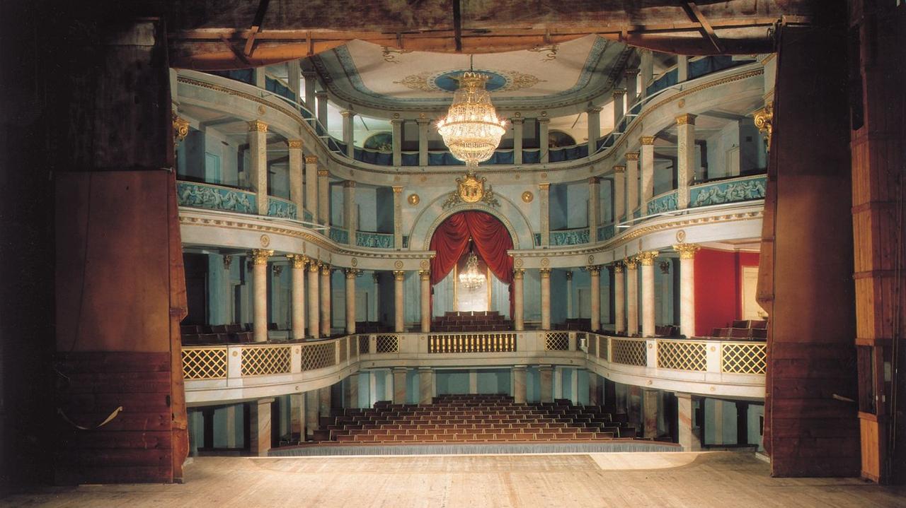 Der Zuschauerraum des Ludwigsburger Schlosstheaters, Blick von der Bühne aus, links und rechts Samtvorhang, Zuschauer-Balkone in barockem Stil