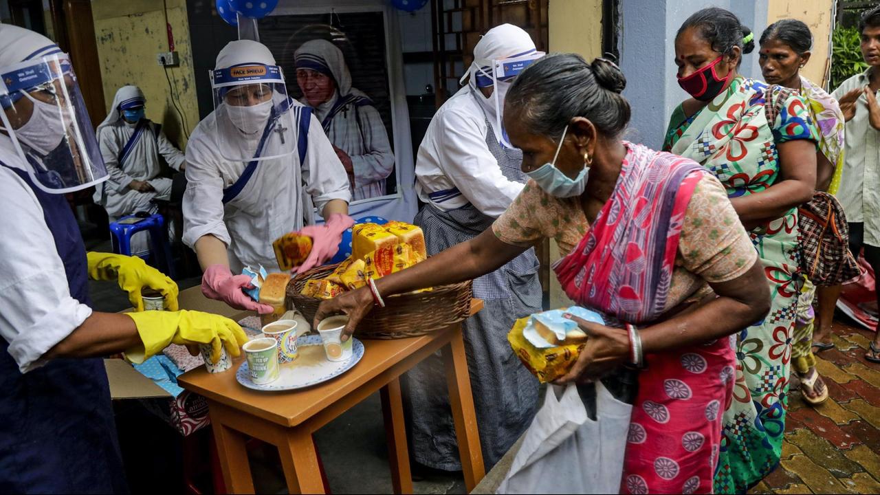 Indien, Kolkata: Nonnen des katholischen Ordens "Missionarinnen der Nächstenliebe", gegründet von Mutter Teresa, tragen Mundschutze und Gesichtsschutze bei der Verteilung von Nahrungsmittel an arme und obdachlose Menschen. 