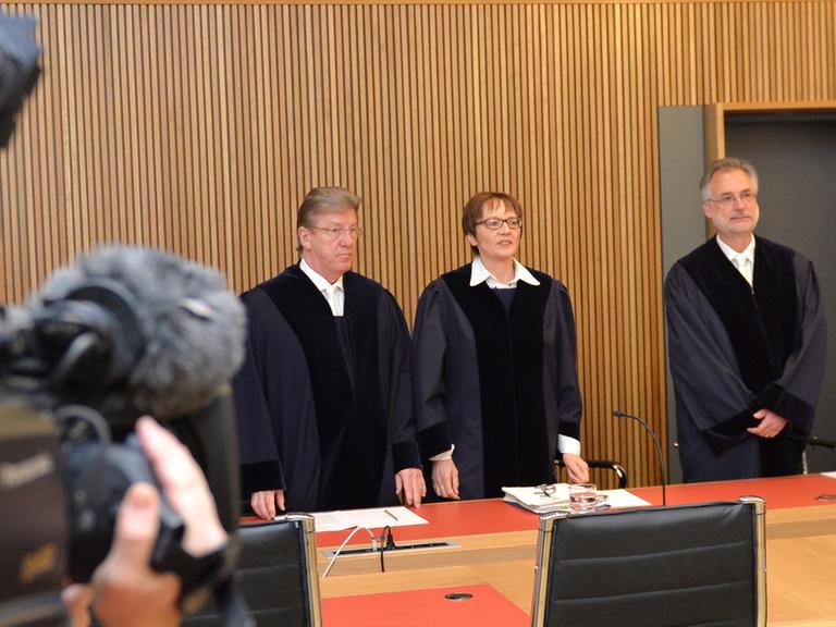 Drei Richter des Strafgerichtshofs in Bremen stehen vor der Urteilsverkündung im Gerichtssaal.