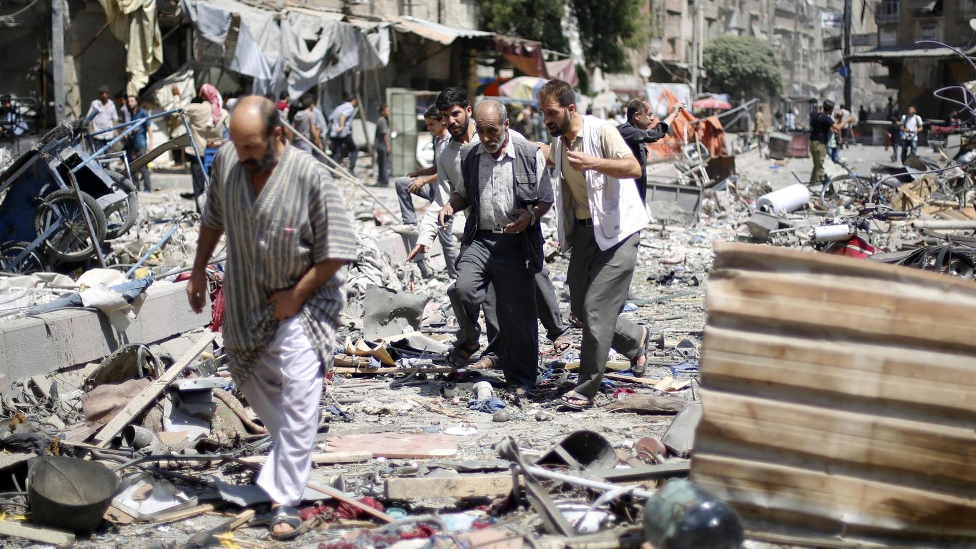 Drei Männer laufen über Schutt auf dem Marktplatz in Duma, Syrien