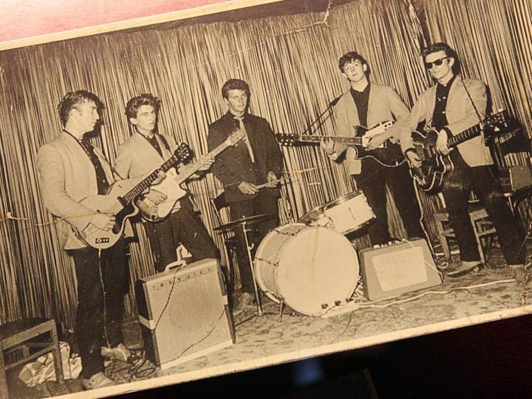 Eine Schwarzweißfotografie auf Papier zeigt die Beatles bei ihrem ersten Auftritt im Hamburger Indra-Club am 17. August 1960.