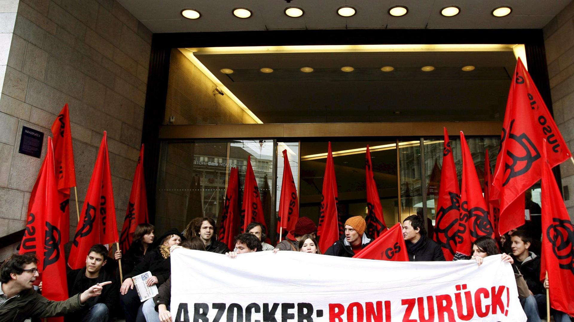 ARCHIV - Mitglieder der Jungen Sozialisten demonstrieren gegen die Boni der Banker vor dem Sitz der größten Schweizer Bank UBS in Zurich am 23.10.2008. Von Novartis bis Nestlé, von Roche bis zur UBS - in Schweizer Weltkonzernen geht Angst vor dem Volk um.