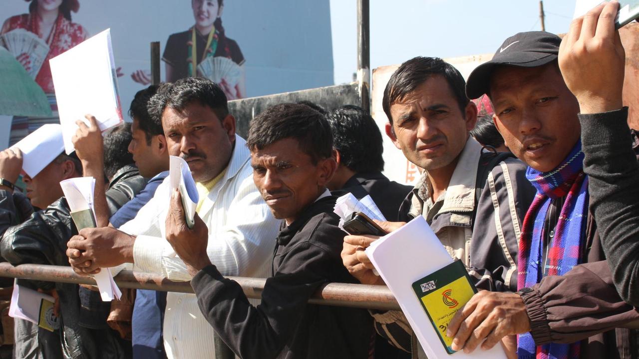 Männer warten vor dem "Department of Foreign Employment" in Kathmandu, Nepal, auf ihre Papiere zur Ausreise.