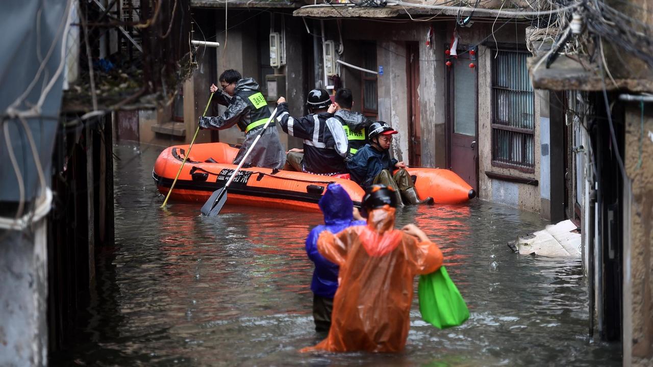 Rettungskräfte fahren in China mit einem Schlauchboot über eine überflutete Straße.