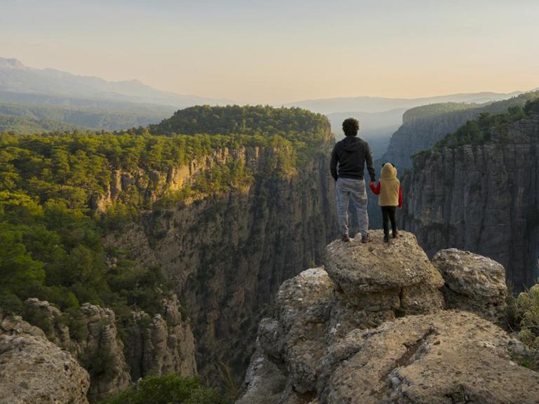 Ein Mann steht mit seinem Kind auf einem Felsen an der Tazi Schlucht in Antalya und schaut in die Ferne