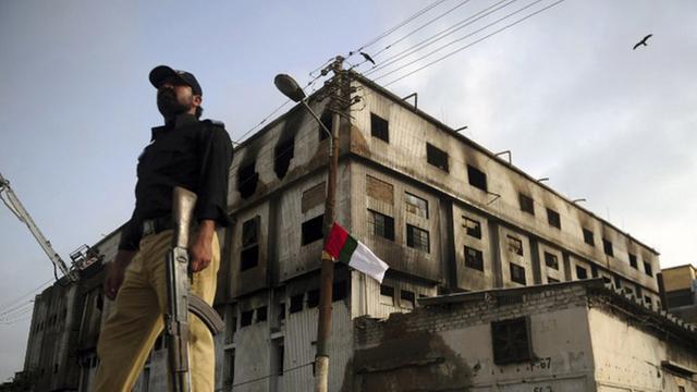 Ein pakistanischer Polizist steht vor der ausgebrannten Textilfabrik in Karachi, in der bei einem Feuer am 14. September 2012 fast 290 Menschen ums Leben kamen.