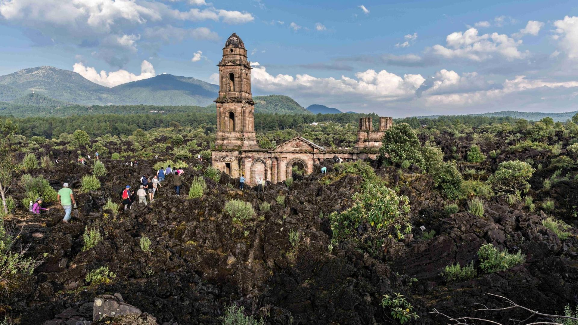 San Juan Parangaricutiro, Michoacan, Mexiko: Touristen klettern im erstarrten Lavagestein, das die Runinen der Kirche von San Juan Parangaricutiro umgibt. Die Kirche ist das einzige Bauwerk, das nach dem achtjährigen Ausbruch des Vulkans Paricutin, der 1943 zwei Dörfer verschlang, übrig blieb.