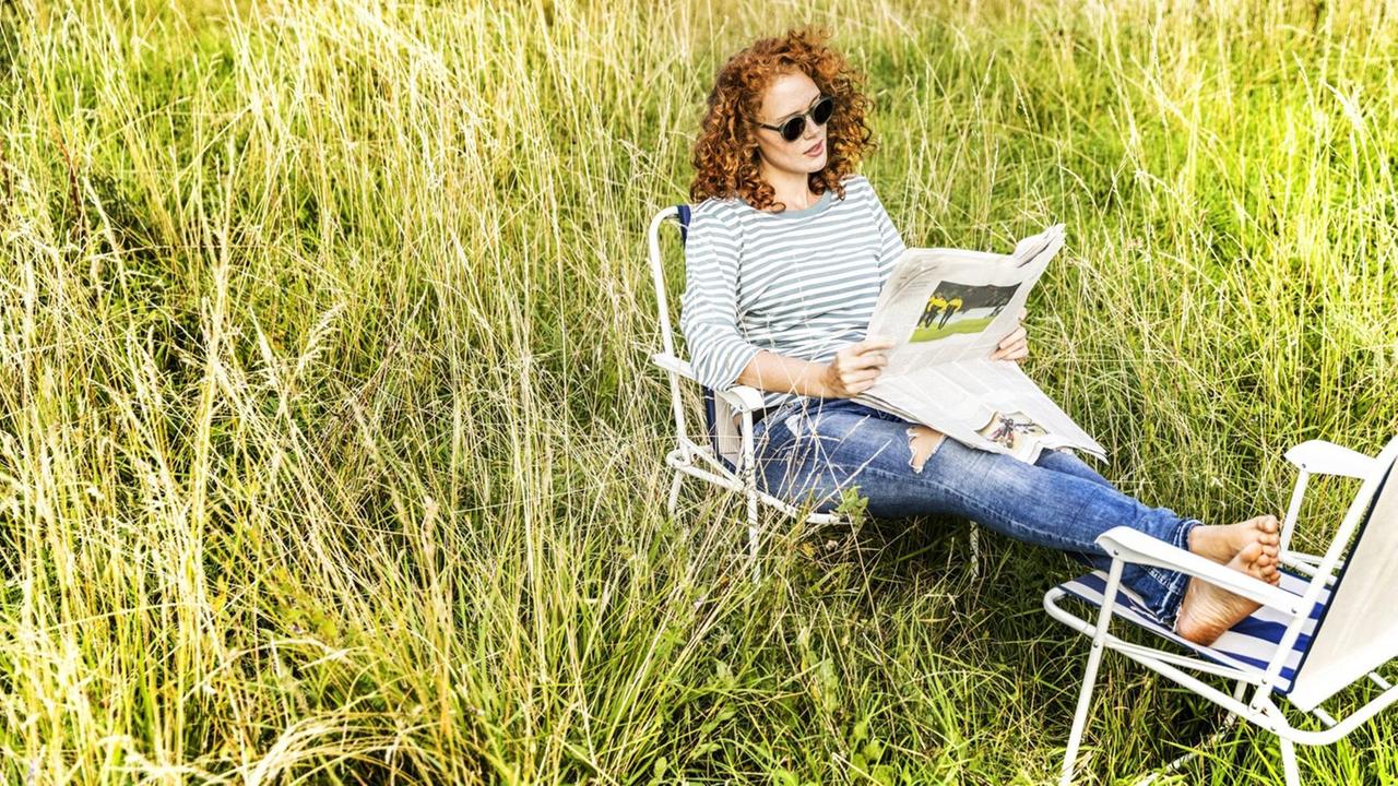 Eine Frau im Grünen liest Zeitung