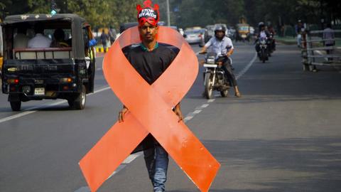 Ein Aktivist trägt ein Aids-Logo um den Körper, das etwa genauso groß ist wie er. Er geht auf einer Straße in Bhubaneswar in Indien.