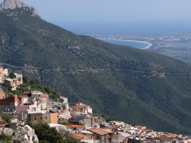 Blick auf die an einem Berghang gelegene Ortschaft Baunei in Sardinien.