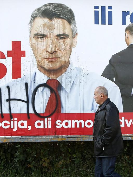 Ein Mann geht an einem Wahlplakat von Zoran Milanovic vorbei