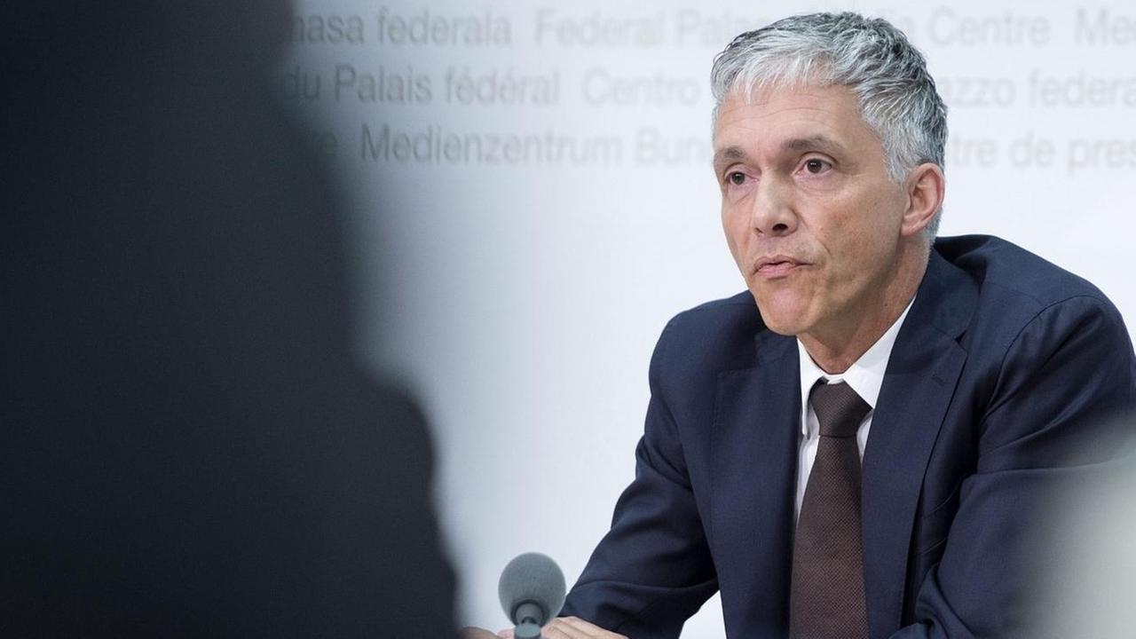 Foto vom oberste Strafermittler der Schweiz, Michael Lauber, bei einer Pressekonferenz durch zwei Journalisten hindurch