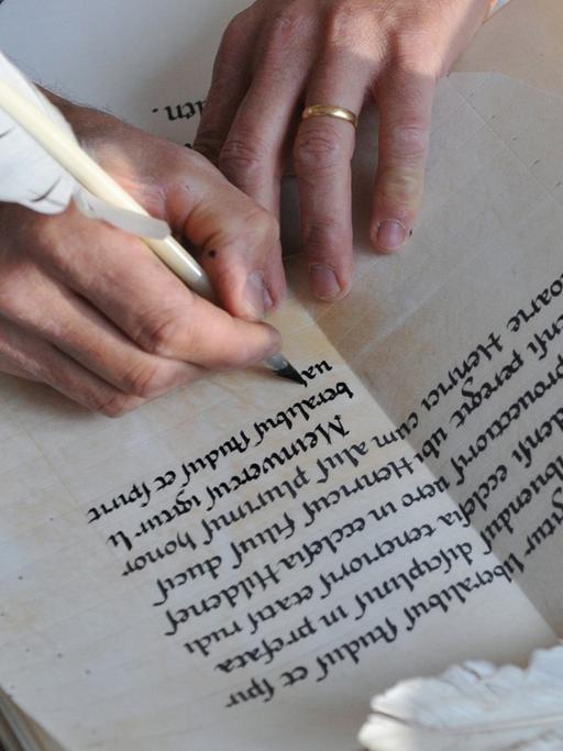 Eine Frau schreibt mit einer Schreibfeder in altertümlicher Schrift.