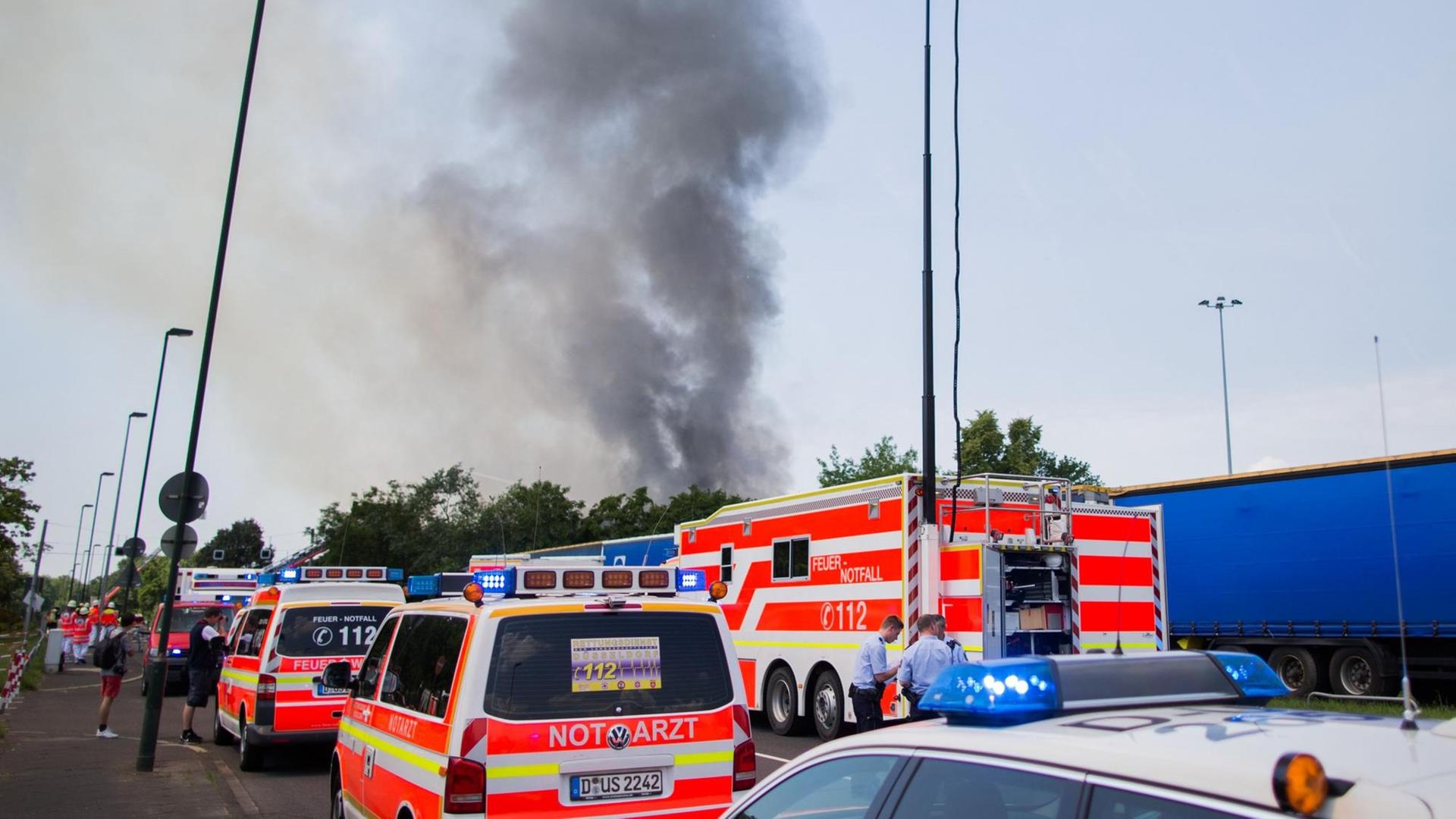 Einsatzwagen stehen am 07.06.2016 am Messegelände in Düsseldorf (Nordrhein-Westfalen) vor einer in Brand geratenen Halle, die als Flüchtlingsunterkunft genutzt wird.