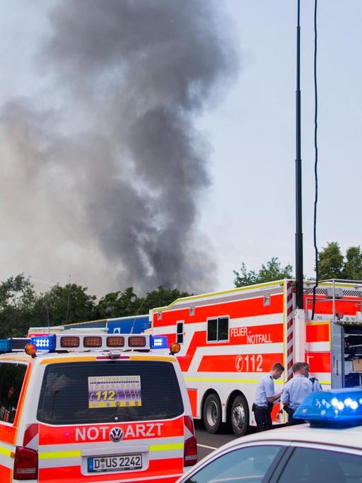 Einsatzwagen stehen am 07.06.2016 am Messegelände in Düsseldorf (Nordrhein-Westfalen) vor einer in Brand geratenen Halle, die als Flüchtlingsunterkunft genutzt wird.