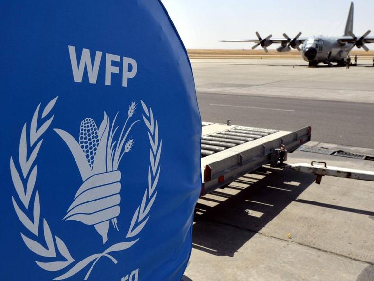 Ein Logo des Welternährungsprogramms World Food Programme und ein belgisches Militärflugzeug auf einem Rollfeld im irakischen Erbil, August 2014