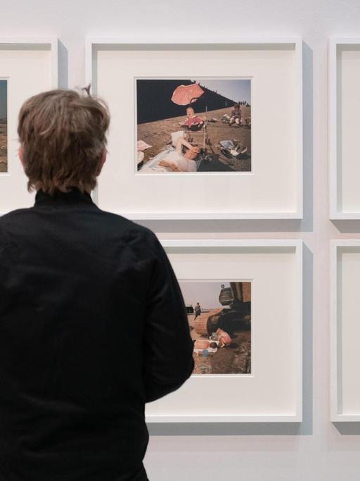 Ein Mann steht in der Ausstellung "[SPACE] Street. Life. Photography. Street Photography aus sieben Jahrzehnten" im Haus der Photography der Deichtorhallen Hamburg vor Werken des Fotografen Martin Parr.