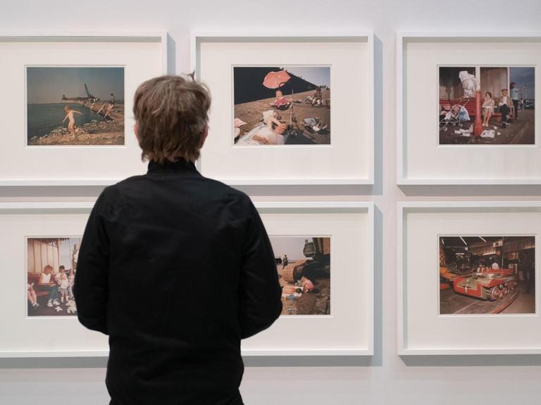 Ein Mann steht in der Ausstellung "[SPACE] Street. Life. Photography. Street Photography aus sieben Jahrzehnten" im Haus der Photography der Deichtorhallen Hamburg vor Werken des Fotografen Martin Parr.