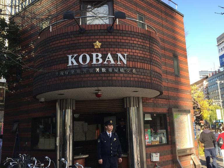 Ein Koban (japanische Mini-Polizeiwache) im Tokioter Bezirk Ginza mit dazugehörigem Polizisten davor. Auf dem Land wohnen die Bezirkspolizisten sogar in ihren Häuschen.