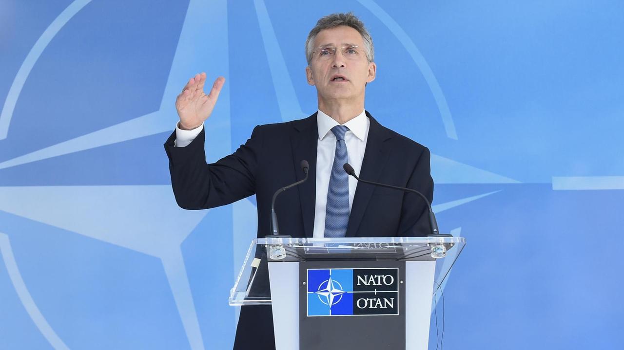Stoltenberg spricht an einem Rednerpult vor einer blauen Wand mit dem NATO-Stern.
