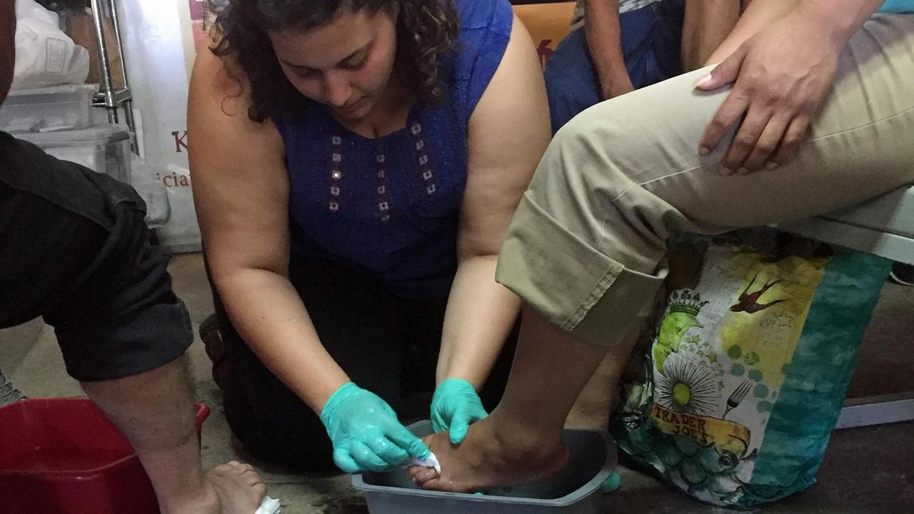 Eine Mitarbeiterin der Kino Border Initiative versorgt den verletzten Fuß eines Migranten.