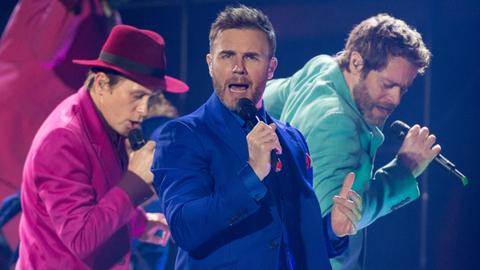 Mark Owen, Gary Barlow und Howard Donald, von Take That, stehen auf der Bühne und singen