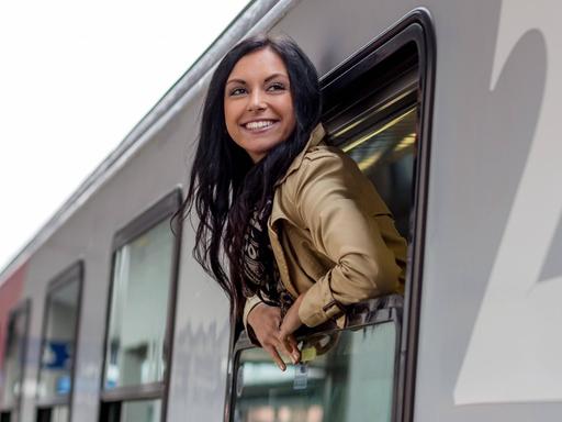 Eine Frau schaut aus dem Fenster eines Zuges im Bahnhof