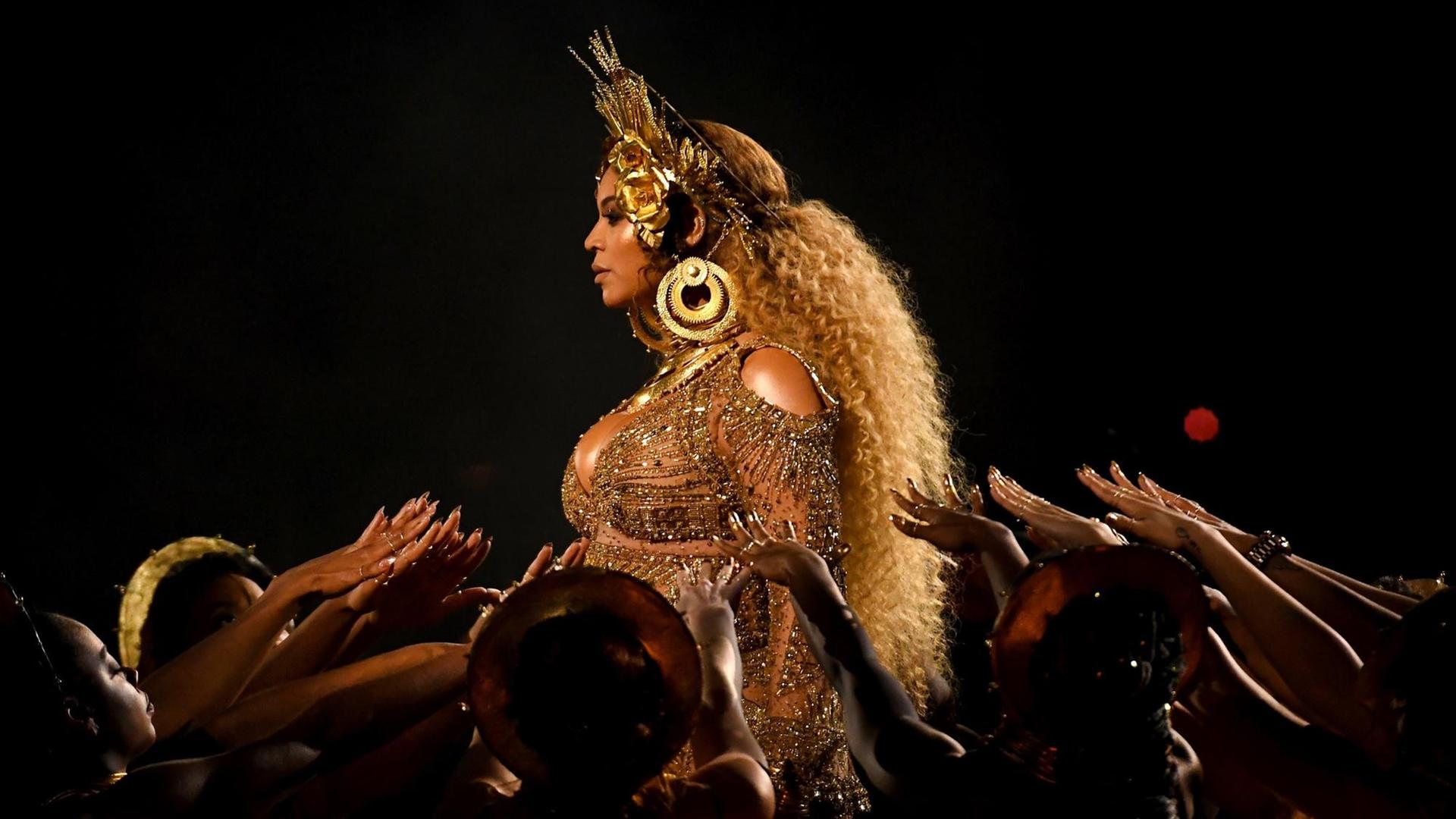 Das Bild zeigt die Musikerin Beyoncé bei einem Konzert vor buntem Effektnebel. Der Podcast "Making Beyoncé" porträtiert die Künstlerin in drei Episoden.