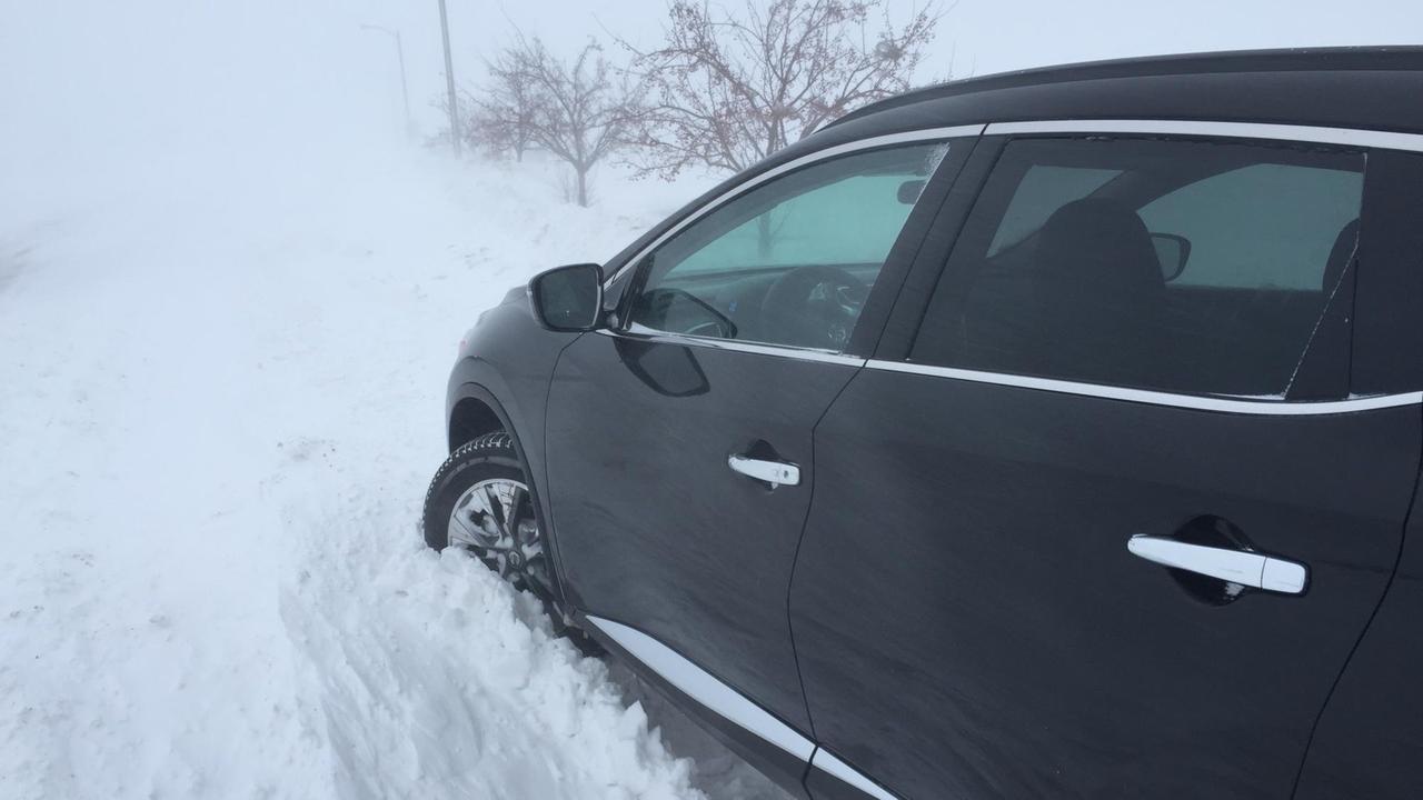 Ein schwarzes Auto steckt im hohen Schnee fest.