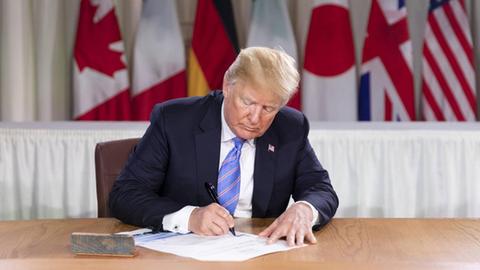 US-Präsident Donald J. Trump unterzeichnet die Liste der Teilnehmer am G7-Treffen in La Malbaie in Kanada. Seine Unterschrift unter die Abschlusserklärung zieht er später zurück.