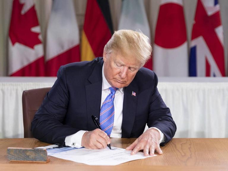 US-Präsident Donald J. Trump unterzeichnet die Liste der Teilnehmer am G7-Treffen in La Malbaie in Kanada. Seine Unterschrift unter die Abschlusserklärung zieht er später zurück.