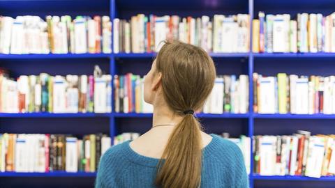 Eine Frau steht vor Bücherregalen.
