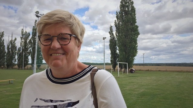 Irmgard Rautenberg ist eine Frau Anfang 60 mit kurzen grauen Haaren. Sie steht am Rande des Fußballplatzes.