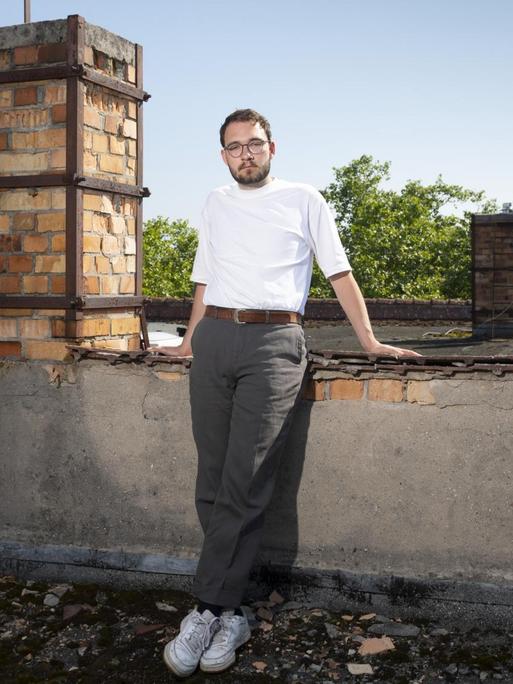 Porträt von Lukas Rietzschel, der auf einem Hausdach neben einem Schornstein posiert.