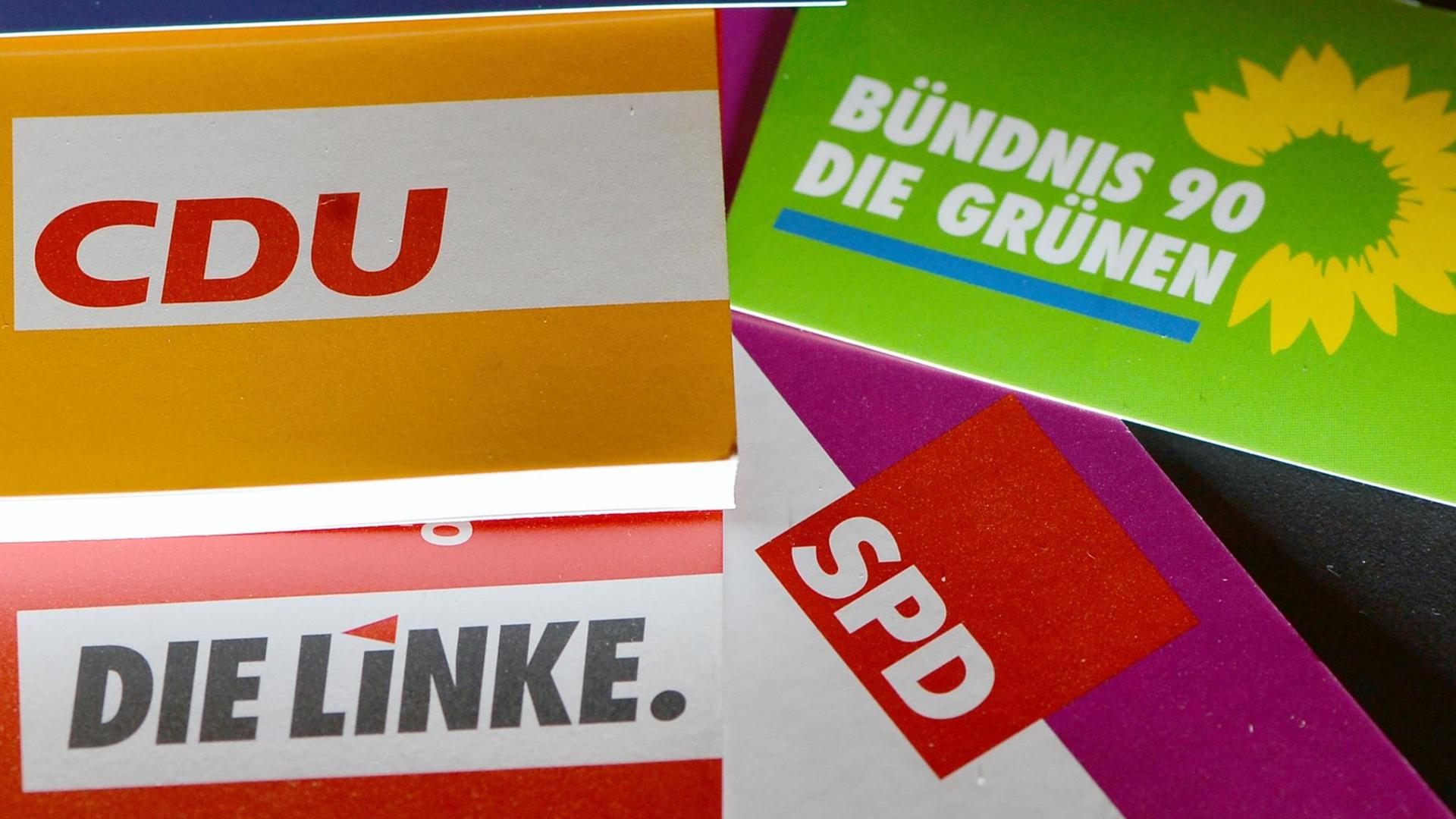 Schriften, Logos und Broschüren von CDU, den Grünen, Die Linke und SPD liegen auf einem Tisch.