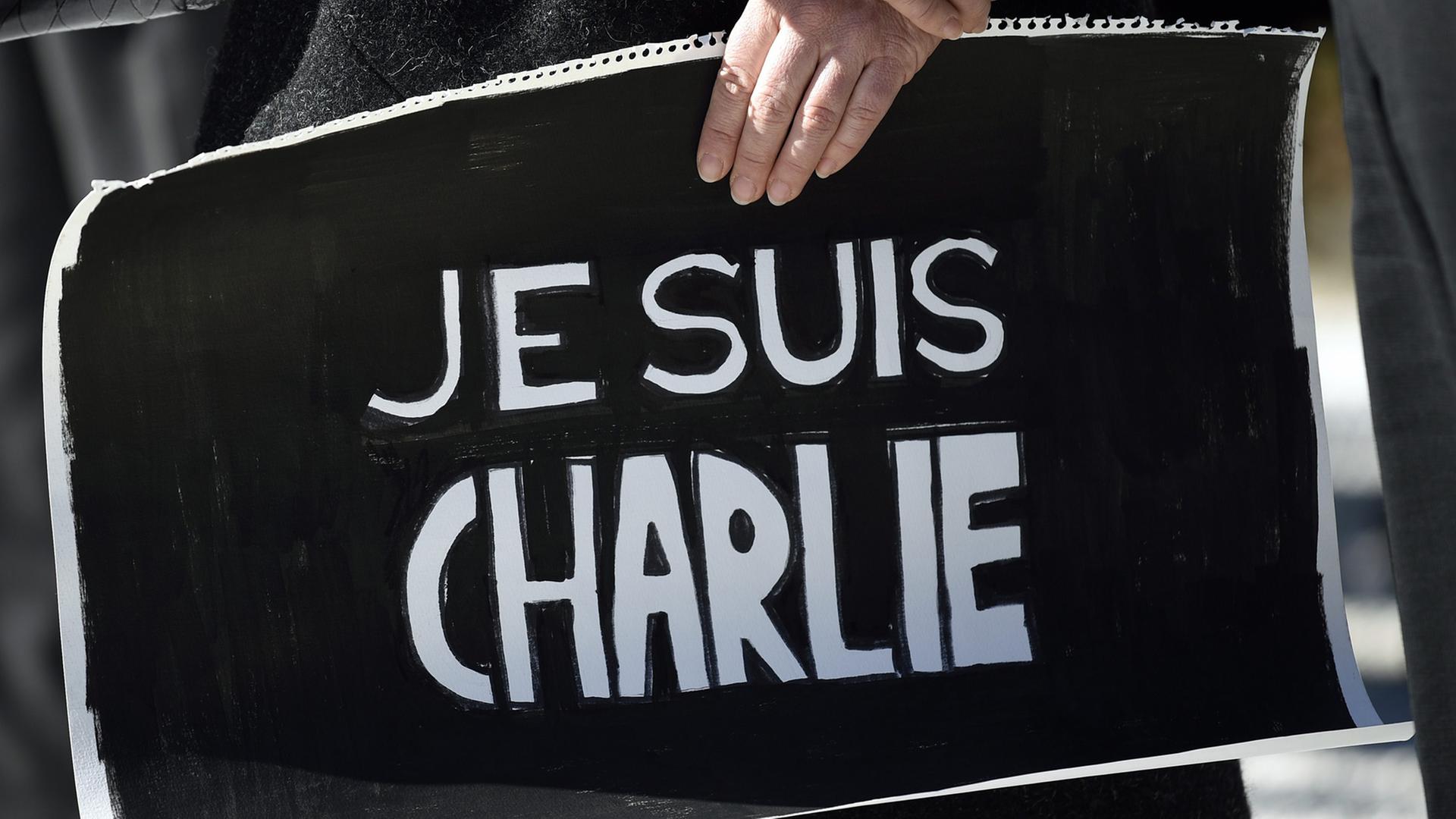 Eine Frau hält vor der französischen Botschaft in Tokio ein Schild mit "Je suis Charlie"