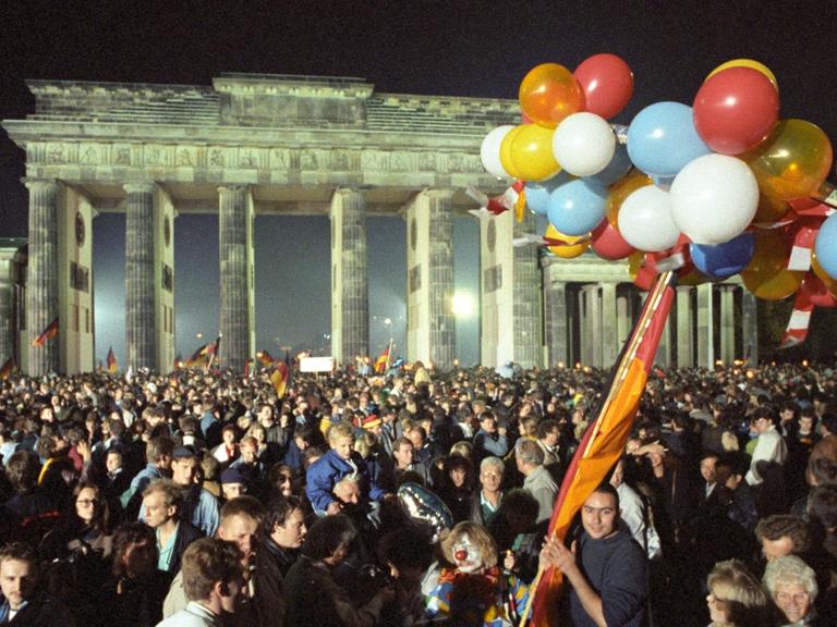 Ausgelassen feiert eine riesige Menschenmenge in der Nacht vom 2. auf den 3. Oktober 1990 vor dem Brandenburger Tor in Berlin die deutsche Wiedervereinigung.