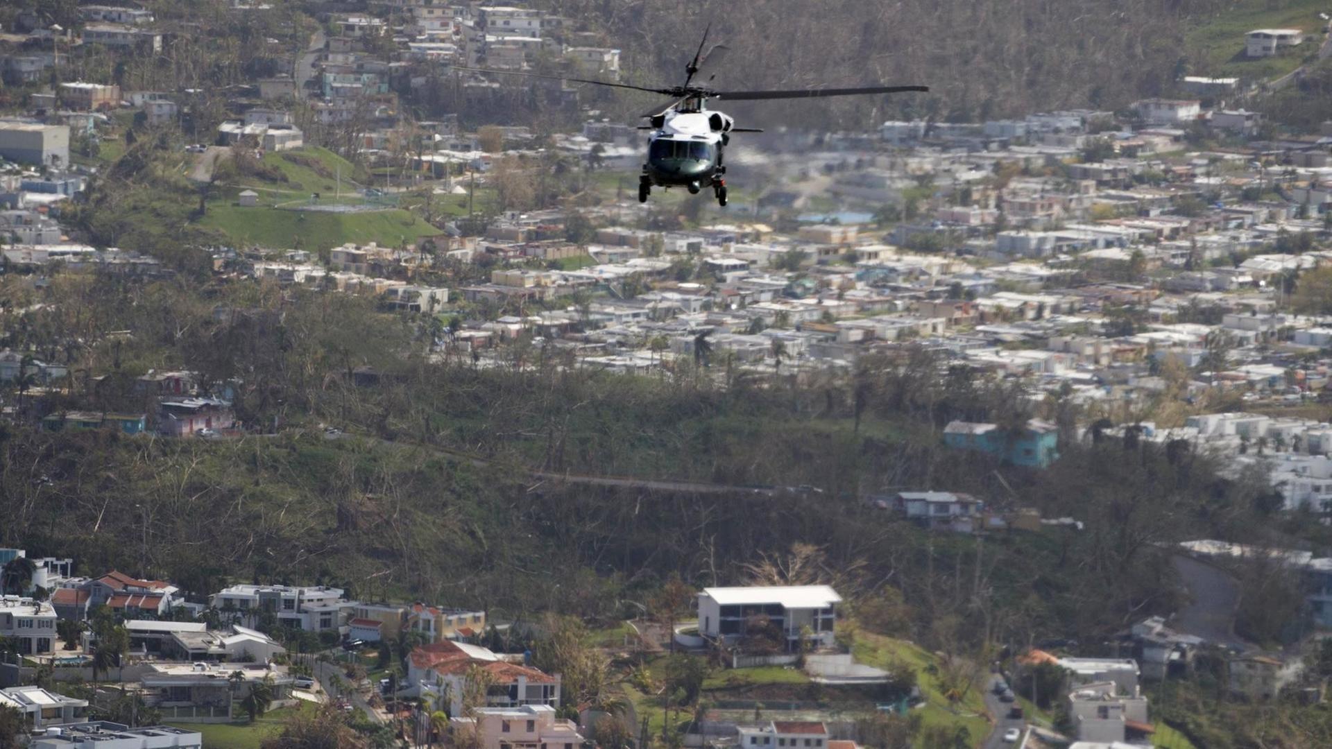Ein Hubschrauber fliegt über eine besiedelte Landschaft.