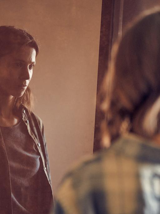 Szene aus der Serie "Unbroken". Alex (Aylin Tezel) steht mit leinem leeren Blick vor einem Spiegel.