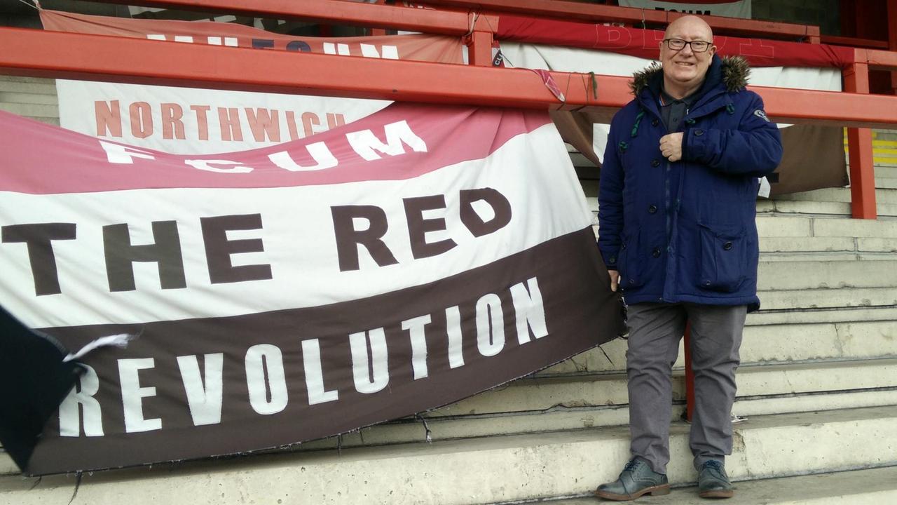 Vinny Thomson posiert im Stadion des FCUM neben einem Banner.