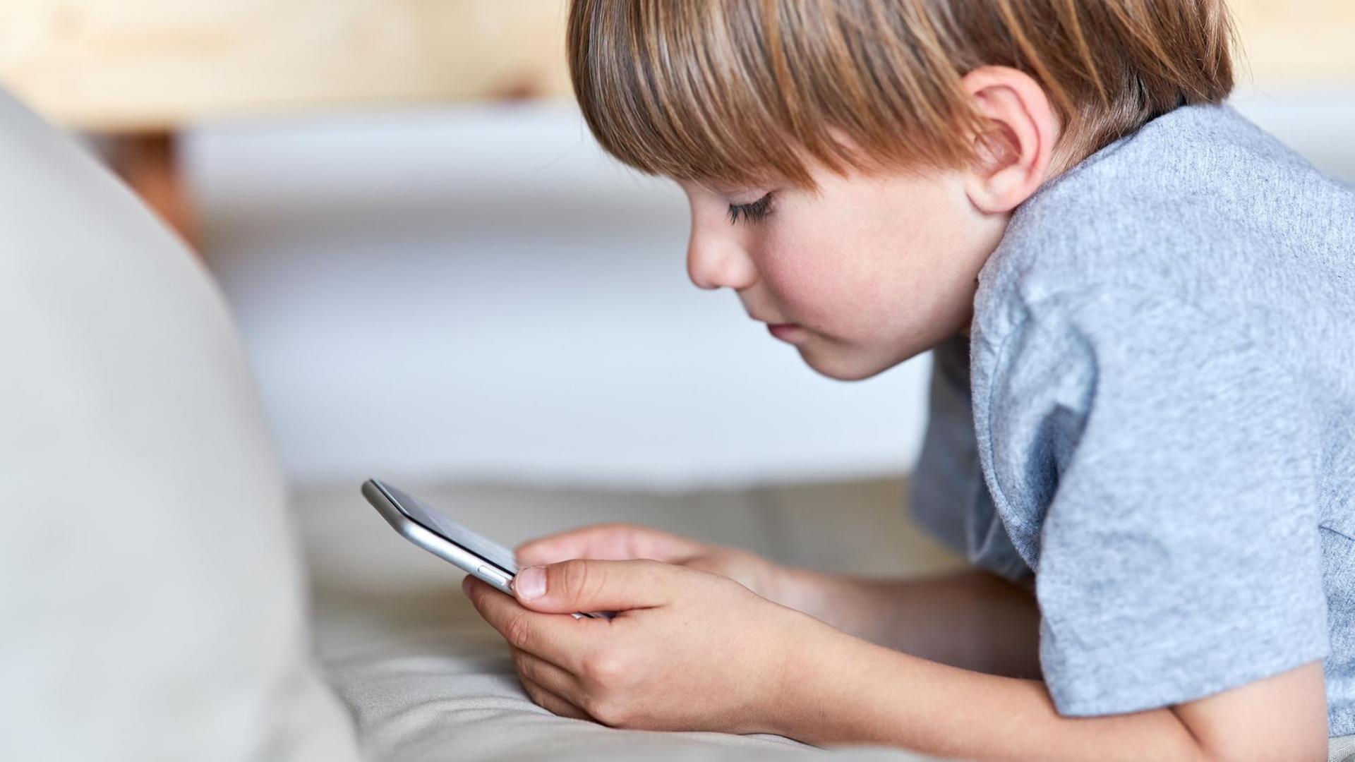 Kleiner Junge schaut auf sein Smartphone Kleiner Junge schaut auf sein Smartphone
