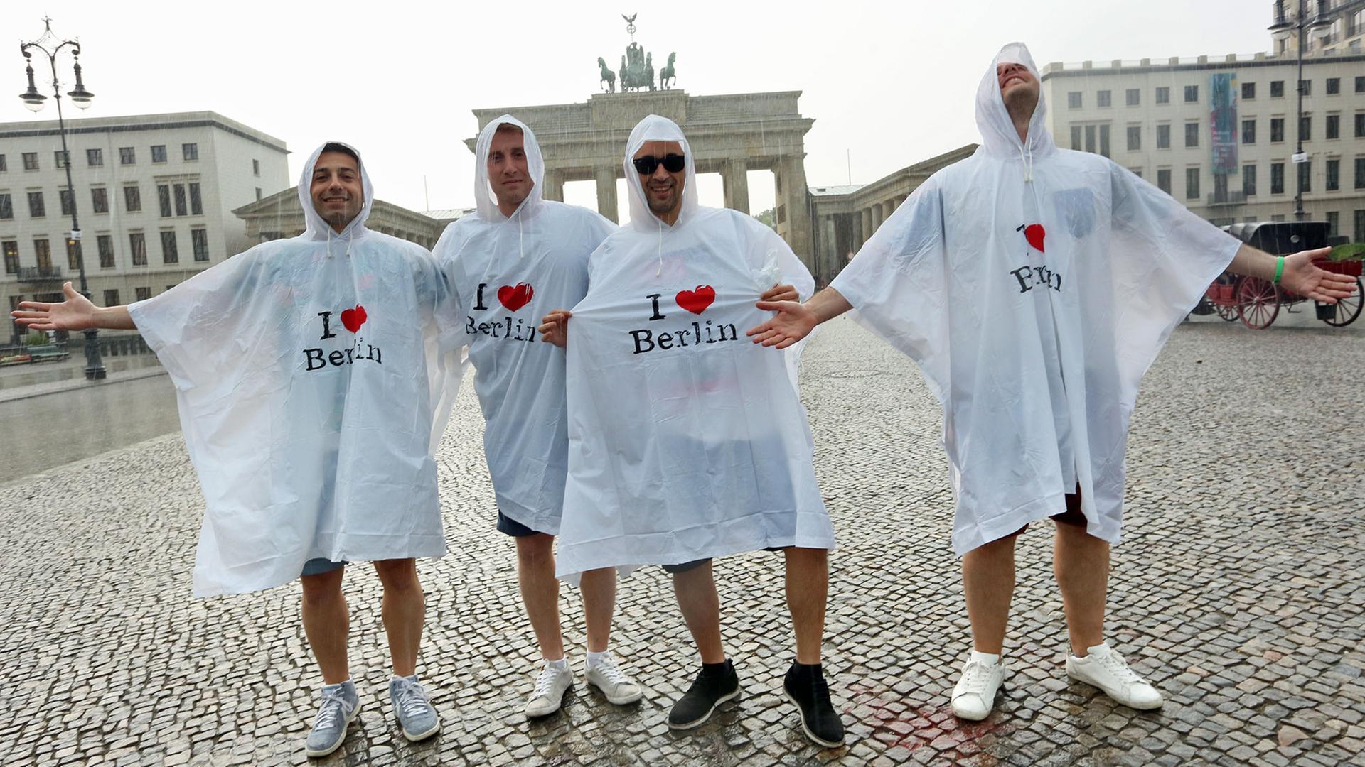 Touristen stehen vor dem Brandenburger Tor in Berlin Grad im Regen.