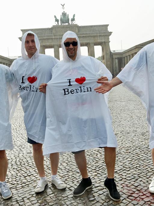 Touristen stehen vor dem Brandenburger Tor in Berlin Grad im Regen.