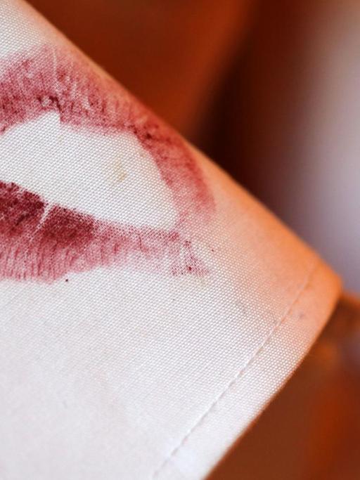 Ein Lippenstift-Kussmund an einem Hemdkragen