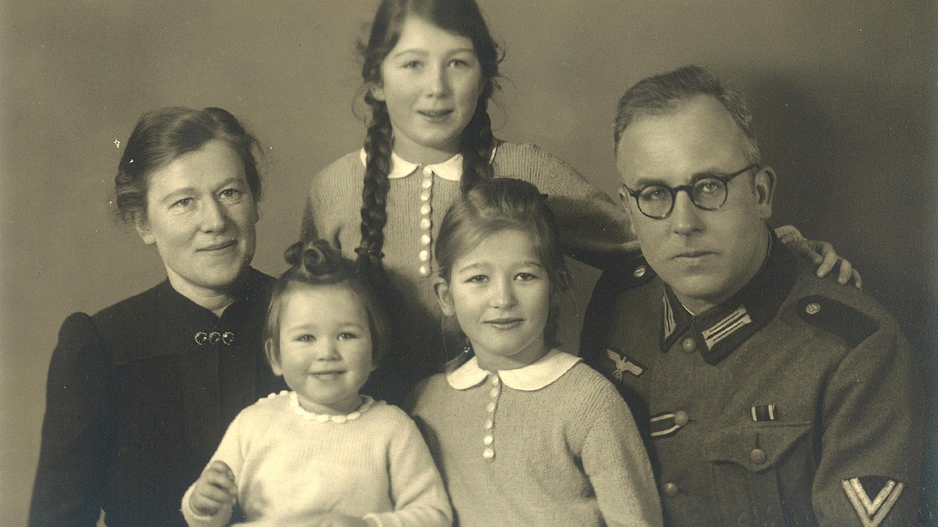 Schwarzweißes Familienfoto. Ein Mann in Uniform mit seiner Frau und drei Kindern.